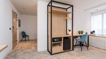 Een moderne keuken met een inbouw houten kast, een zwarte koelkast, een aanrecht en een raam met dunne gordijnen.