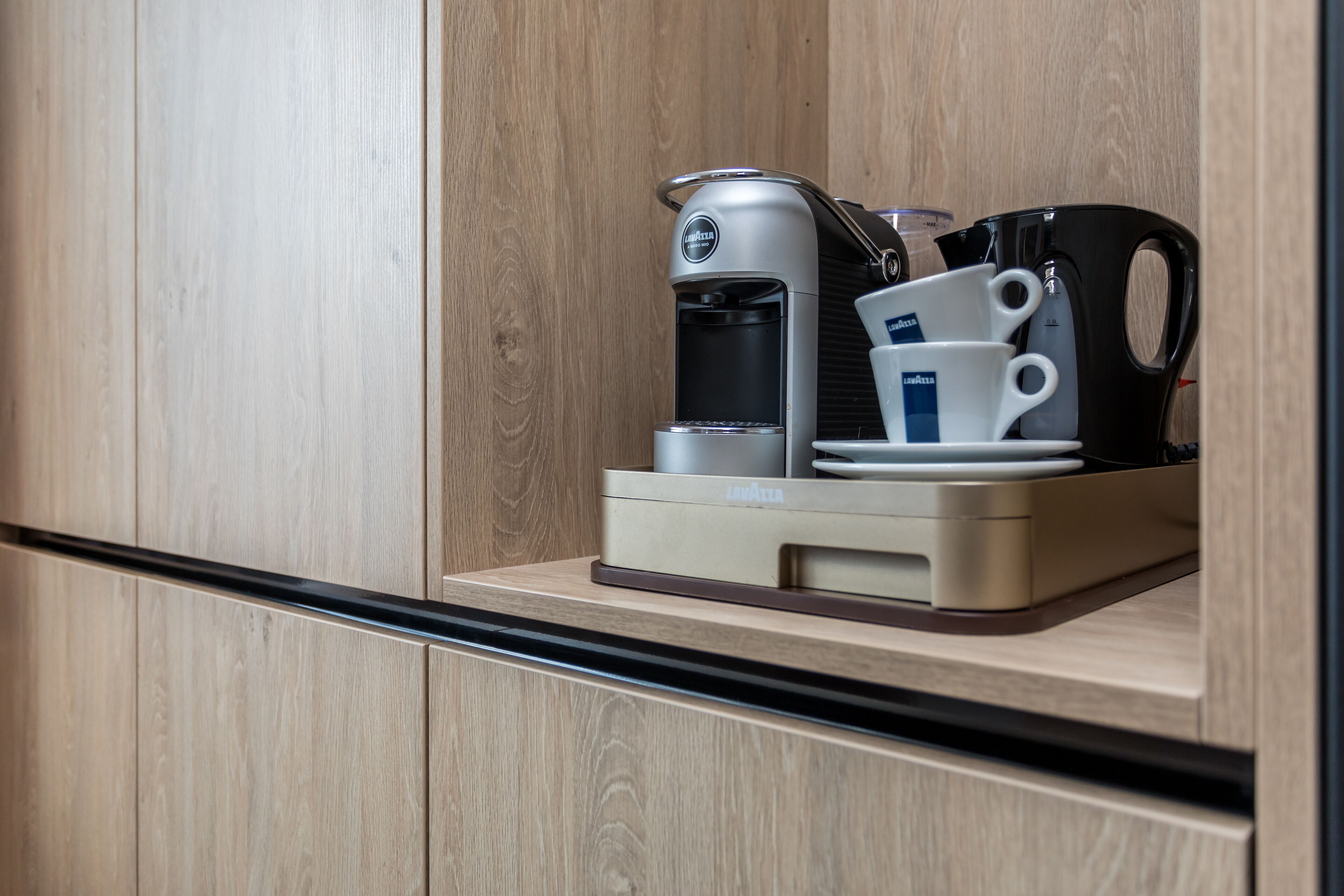 Une machine à café, avec une tasse et une soucoupe, posée sur un comptoir en bois.
