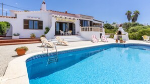 Et hus med swimmingpool, udendørs møbler og en patio.