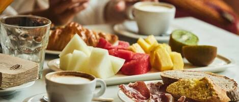 A breakfast setting with plates of food, coffee, and a glass of water.