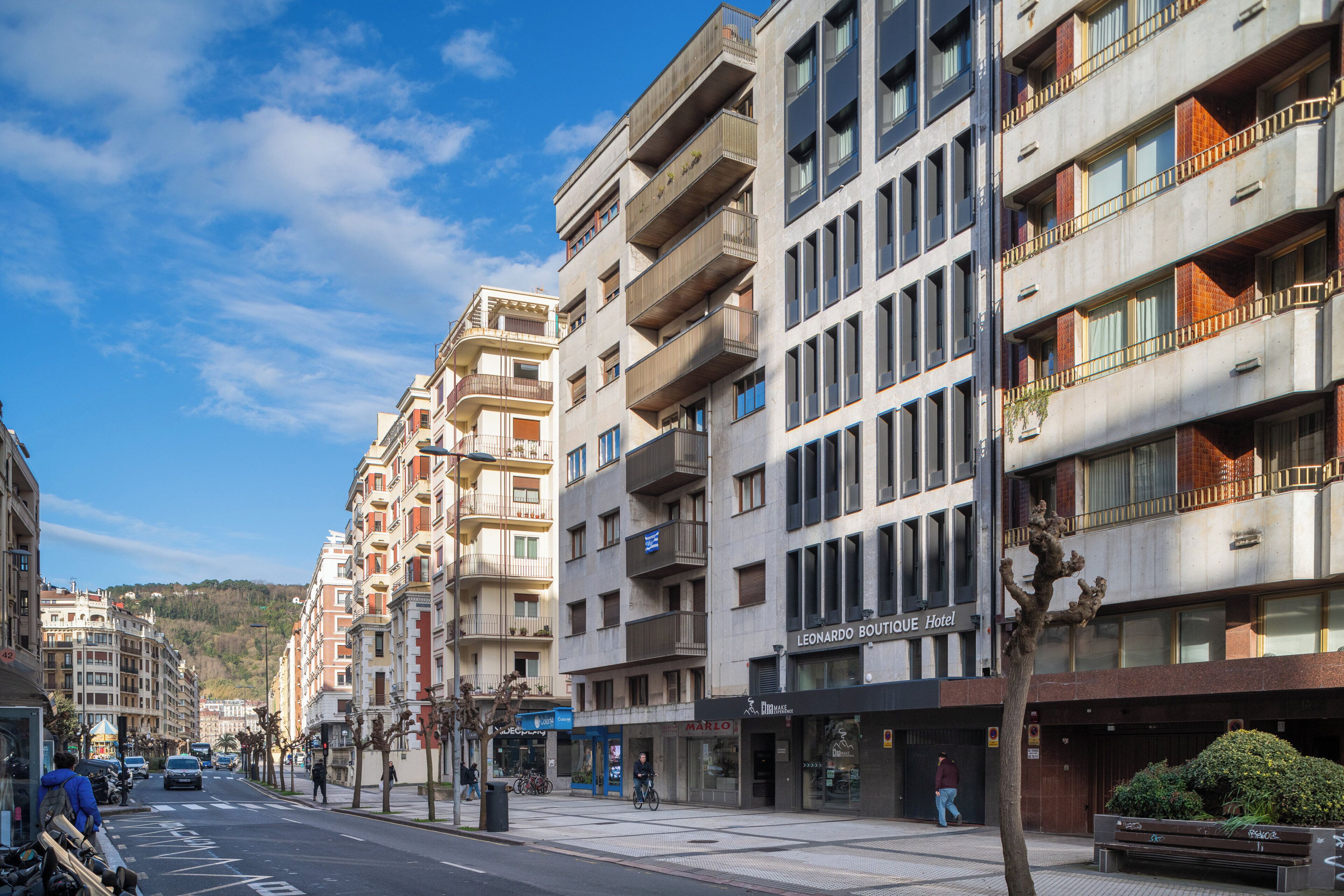 A multi-story hotel with balconies, a storefront, and a bike parking area.