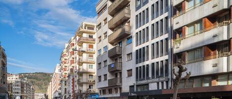 Un hotel de varios pisos con balcones, una fachada comercial y un área para estacionamiento de bicicletas.