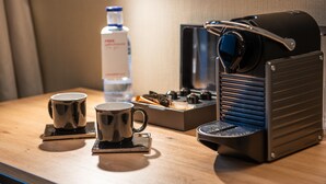 A coffee machine, two cups, and a bottle of water on a wooden table. - Leonardo Boutique Hotel San Sebastián (San Sebastián)