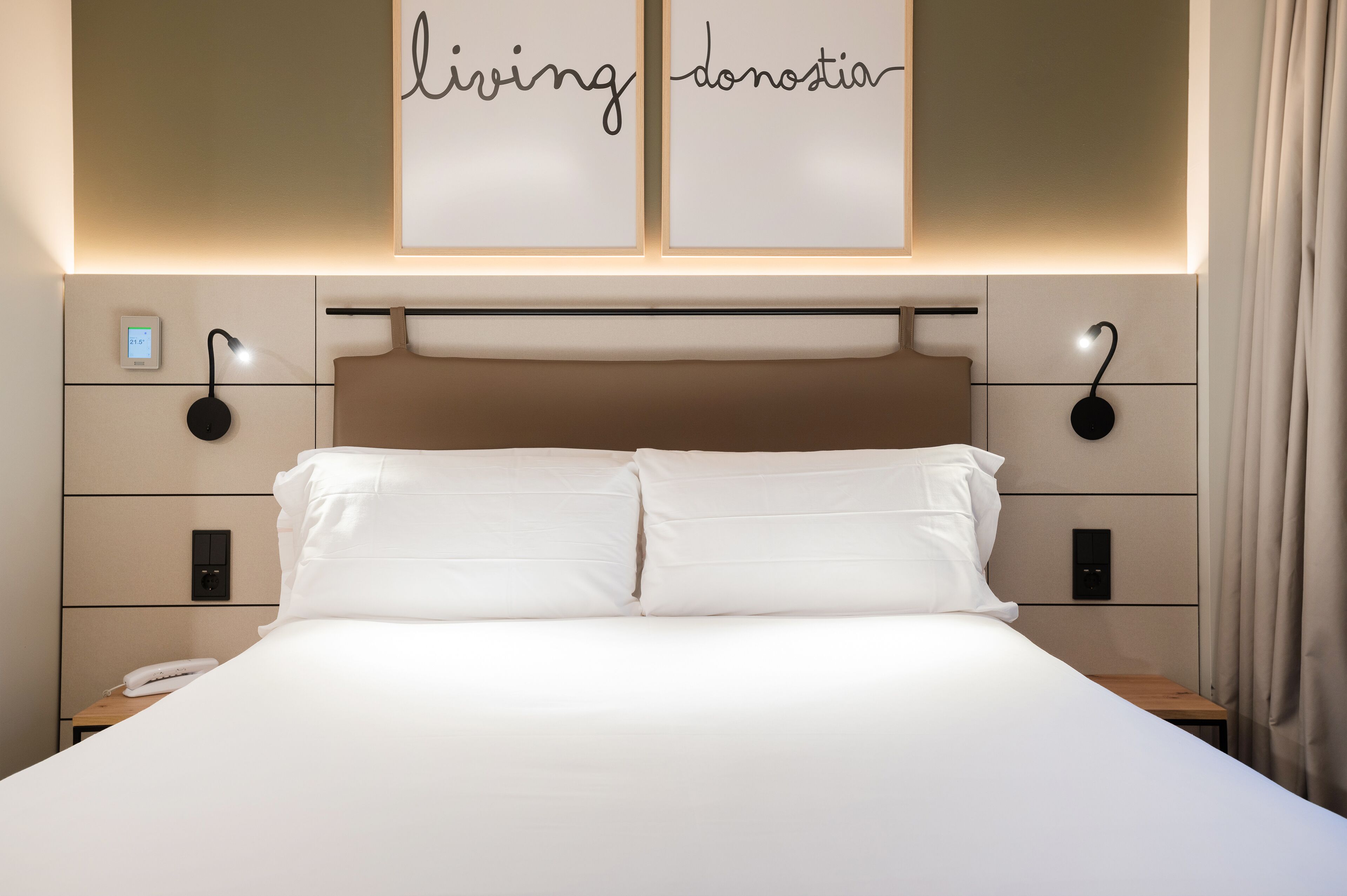 Une chambre d’hôtel moderne, dotée d’un grand lit, de tables de chevet et d’un système d’éclairage mural.