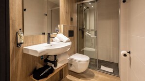 A modern bathroom with a wooden vanity, a white sink, a toilet, and a glass-enclosed shower. - Leonardo Boutique Hotel San Sebastián (San Sebastián)