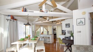 Une cuisine spacieuse avec des poutres en bois, un coin repas avec un banc et un coin salon confortable avec un canapé à motifs.