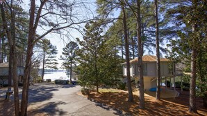 Un quartier résidentiel avec une maison, une allée et un lac en arrière-plan.