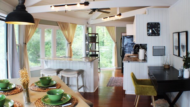Une cuisine moderne avec un coin repas, un plancher en bois et de grandes fenêtres.