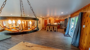 Een ruime keuken met een centraal kookeiland, houten vloeren en een hangende lamp.
