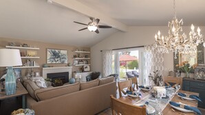 A living room with a sofa, dining table set for four, and a fireplace. - 3827 Betsy's Nest - Adorable Monterey Cottage (Monterey)