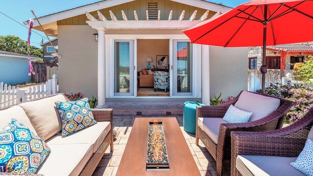 A patio with wicker furniture, a red umbrella, and a fire feature. - 3827 Betsy's Nest - Adorable Monterey Cottage (Monterey)