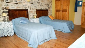 A bedroom with two beds, wooden headboards, a stone wall, and a wooden door. - Charming gîte in the heart of the vineyards - Swimming pool, Jacuzzi & Air conditioning (Fressac)