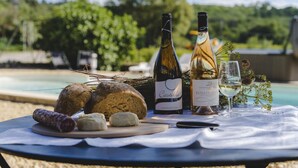 A picnic setup with bread, cheese, and wine bottles on a table by a pool. - Charming gîte in the heart of the vineyards - Swimming pool, Jacuzzi & Air conditioning (Fressac)