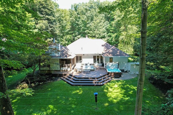 A house with a deck, a hot tub, and a covered patio area.