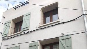 A multi-story building with a white facade, green shutters, and a visible door marked with the number 8. - Charmante Maison Avec Toit Terrasse (Montalba-le-Château)
