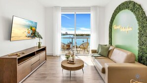A modern living room with a wooden TV stand, a round coffee table, a sofa, and a view of the sea through large windows. - Hollywood Beach|Front Bay View  - Amazing Pool (Hollywood)