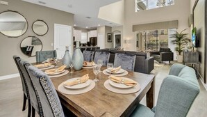 A spacious dining area with a large wooden table set for six, surrounded by upholstered chairs. - "boutique" Style Home Near Disney! 5 Bedroom Home by RedAwning (Kissimmee)
