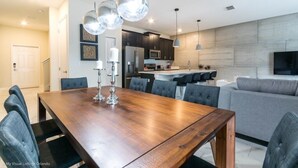 A modern kitchen with dark cabinets, a stainless steel refrigerator, and a microwave. - Luxury Champions Gate Town Home 4 Bedroom Townhouse by RedAwning (Davenport)