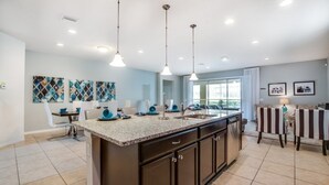 A modern kitchen with a large island, dark cabinetry, and pendant lighting. - 8 Bed Windsor At Westside Resort! 8 Bedroom Villa by RedAwning (Kissimmee)