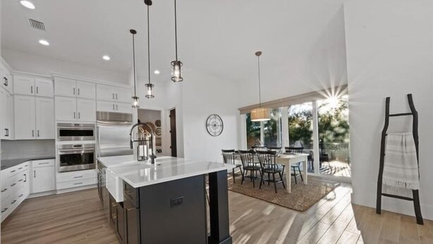 A modern kitchen with white cabinets, a central island, and pendant lighting.