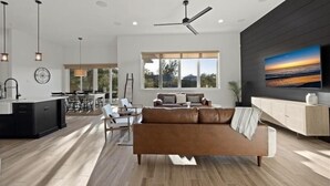 A modern living room with a sofa, dining area, and kitchen.