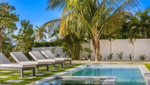 A swimming pool with lounge chairs and palm trees.