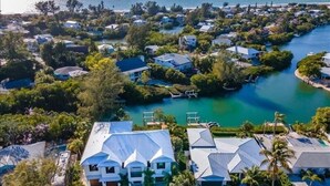 An aerial view of a coastal residential area with houses, a swimming pool, and a marina.