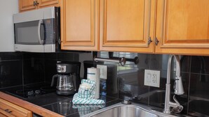 A kitchen with a microwave, coffee maker, sink, and wooden cabinets.
