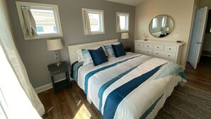 A bedroom with a bed, bedside tables, a dresser, a mirror, and a ceiling fan. - Waterfront: Dock Access, Walk to Beach, Pier & Shops, 5BR, Sunset view / 10% off (Surf City)