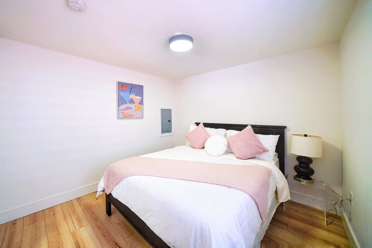 A bedroom with a bed, a nightstand, a lamp, and a wall-mounted light fixture.