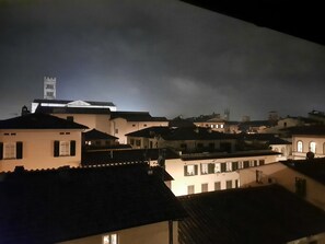 A nighttime view of a town with buildings and a prominent tower. - THE TERRACE BETWEEN THE TOWERS (Lucca)