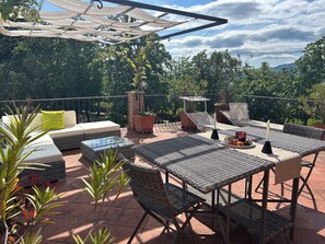 An outdoor patio with a sofa, chairs, a table, and potted plants. - THE TERRACE BETWEEN THE TOWERS (Lucca)