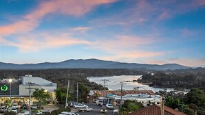 A view of a town with a river, mountains in the background, and a parking lot with cars. - With stunning ocean views and open living, enjoy the coastal lifestyle of Beauty on Bowra. (Nambucca Heads)