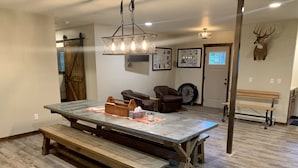 A dining area with a large wooden table, benches, and a chandelier. - Home On Bike/Snowmobile/UTV-ATV Trail Near Chain of Lakes and Town! (Manitowish Waters)