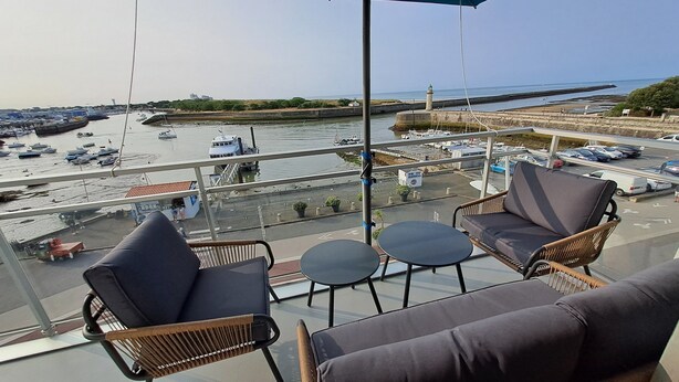A balcony with wicker furniture and a view of a marina with boats.