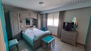 A bedroom with a bed, a dresser, a television, and a small table.