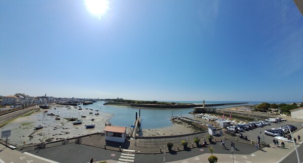 A coastal marina with boats, a small building, and a paved area with cars and people. - Saint Gilles Croix de Vie facing the sea (l'Adon). (Saint-Gilles-Croix-de-Vie)