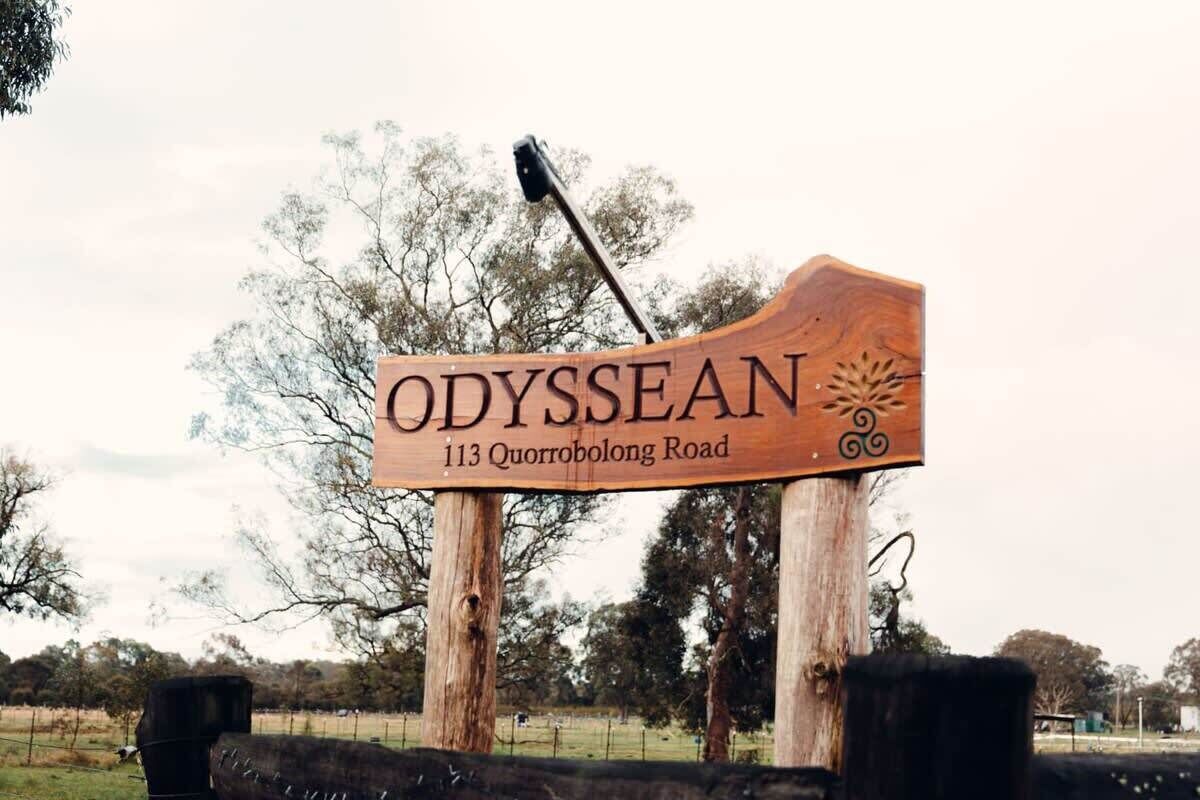 Een houten bord met de naam 'ODYSSEAN' en het adres '113 Quorrabolong Road'.