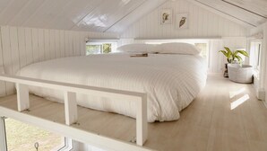Une chambre avec un grand lit, un plafond en bois et une fenêtre.
