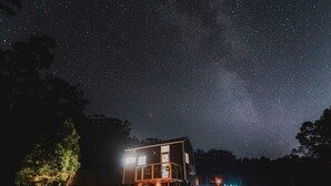 Une maison dotée d’un balcon, sous un ciel étoilé.