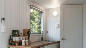 Une cuisine de taille réduite, dotée d’un plan de travail en bois, d’un évier et d’une fenêtre.
