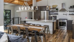 A modern kitchen with stainless steel appliances, a wooden dining table, and a black and white color scheme.