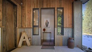 A wooden exterior with a large 'A' sign, a framed picture above the door, and a metal barrel to the right.