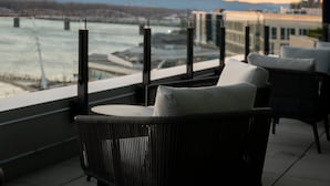 Een balkon met rieten stoelen en uitzicht op een rivier en een brug.