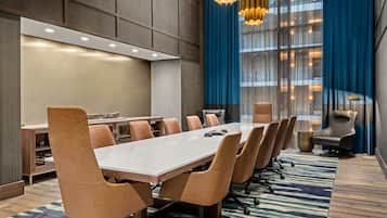 Un salón de conferencias con una larga mesa, varias sillas y una moderna lámpara de araña.