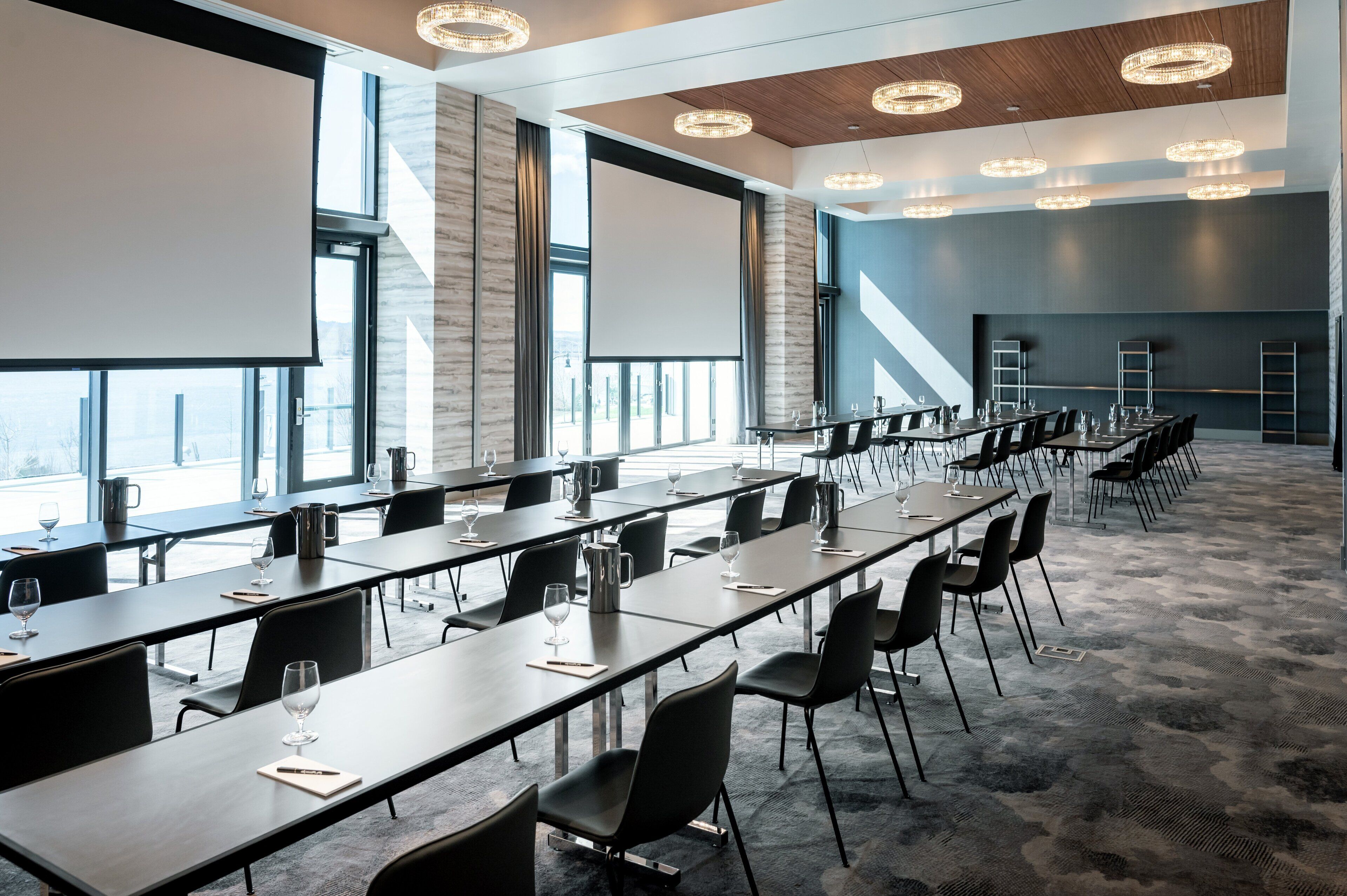 Un salón de conferencias con mesas largas, sillas y una pantalla grande.