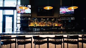 A bar area with multiple TVs, a well-stocked liquor shelf, and leather bar stools.