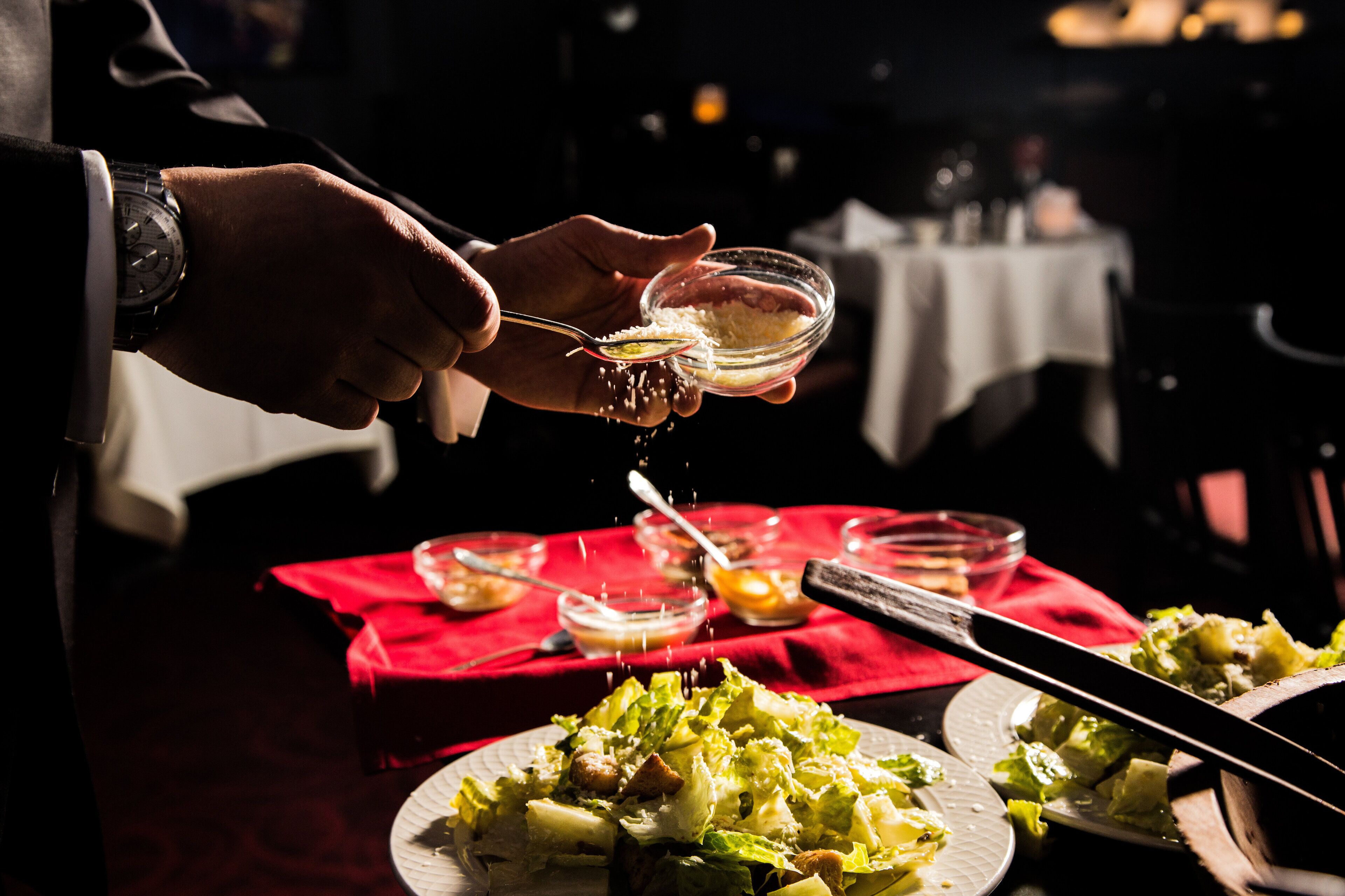 A person seasoning a salad with a spoon.