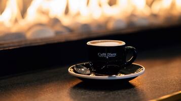 A cup of coffee on a saucer with a blurred background of a fireplace.