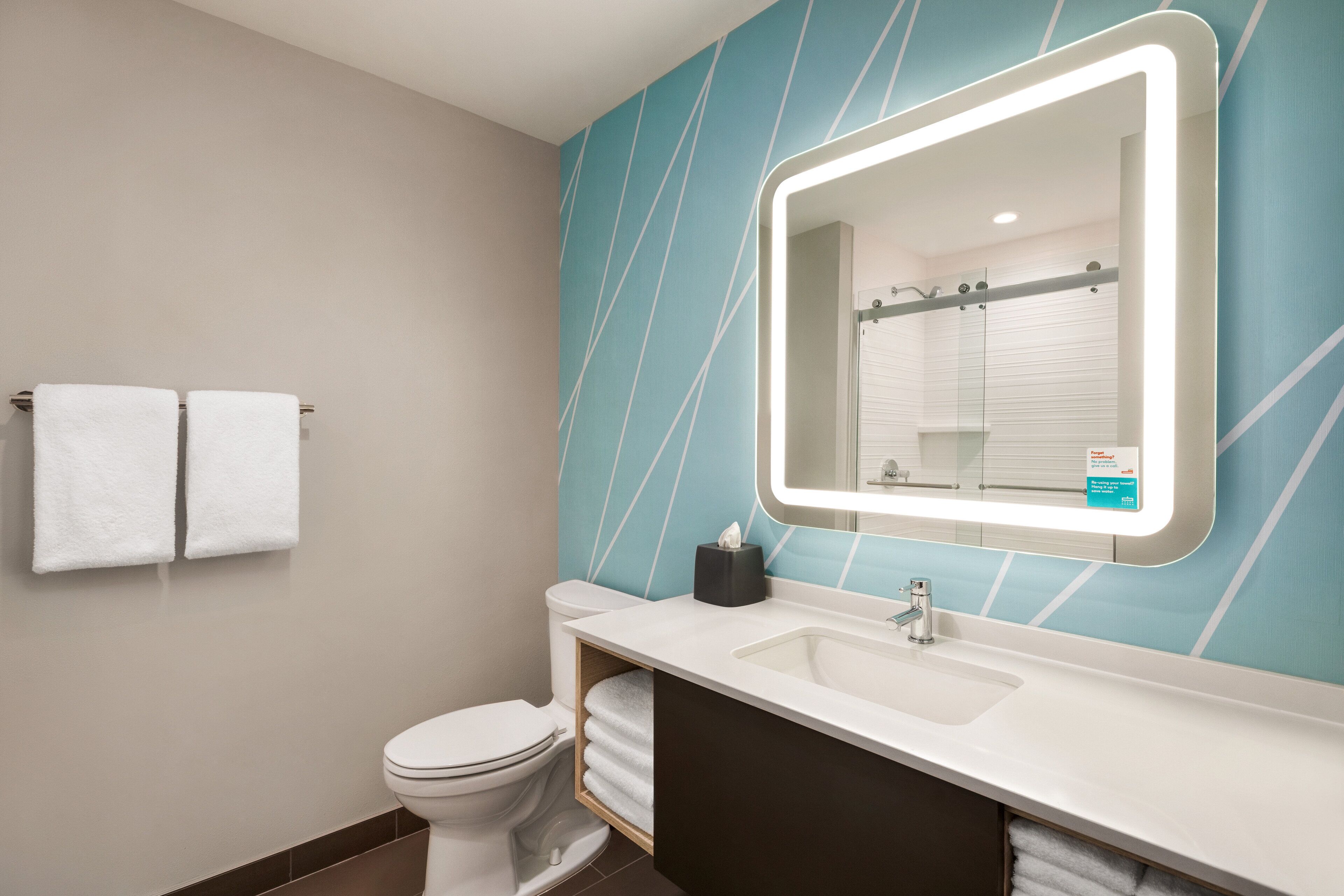A modern bathroom with a white sink, a large mirror, and a toilet.